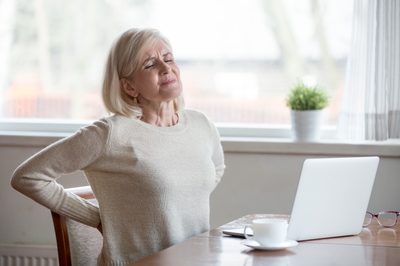 Mujer madura de mediana edad molesta siente dolor de espalda masajeando músculos doloridos, señora mayor triste sufre dolor lumbar sentado en postura sedentaria incorrecta, dolor de espalda radiculitis concepto