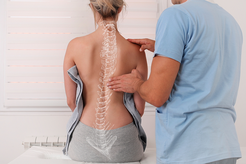 médico revisando la columna vertebral de una mujer.  