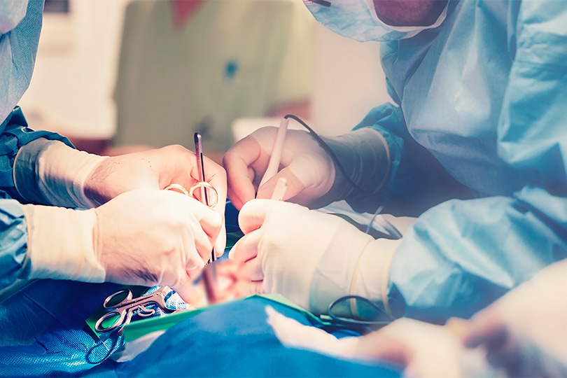 A surgeon in scrubs performing surgery on a patient on an operating table in a sterile environment.
