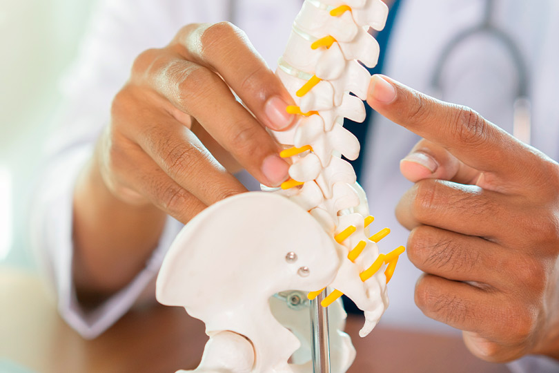  A doctor holds a spine model, showcasing expertise in pain management at Mission's top specialists.