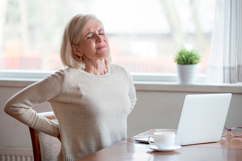A woman seated at a table, viewed from behind, engages in a conversation about spinal cord stimulation for seniors.