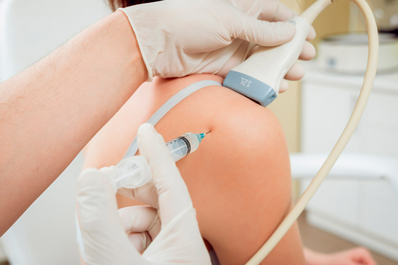 An individual getting an injection from an advanced machine, showcasing the integration of traditional and modern pain relief methods.