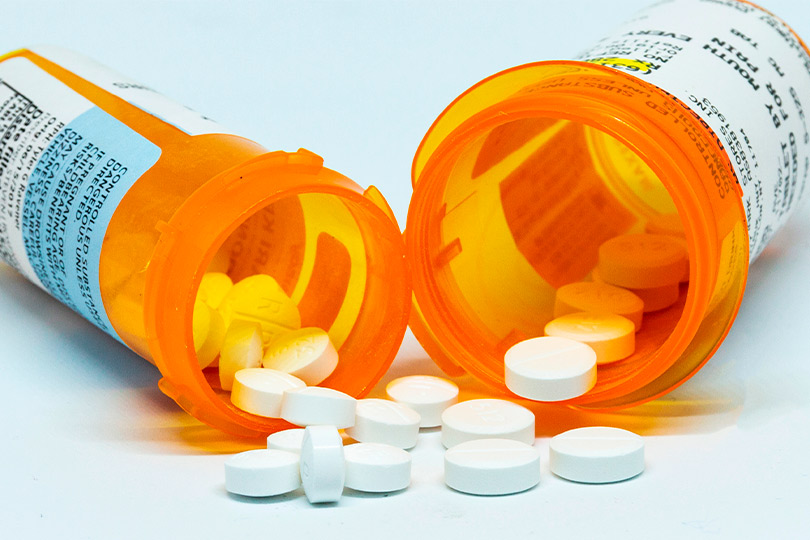 An open prescription bottle with pills scattered around, representing the struggle with pain dependency and recovery.