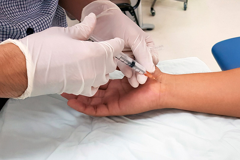 Individual getting an injection in the arm, related to steroid treatment for back pain management.
