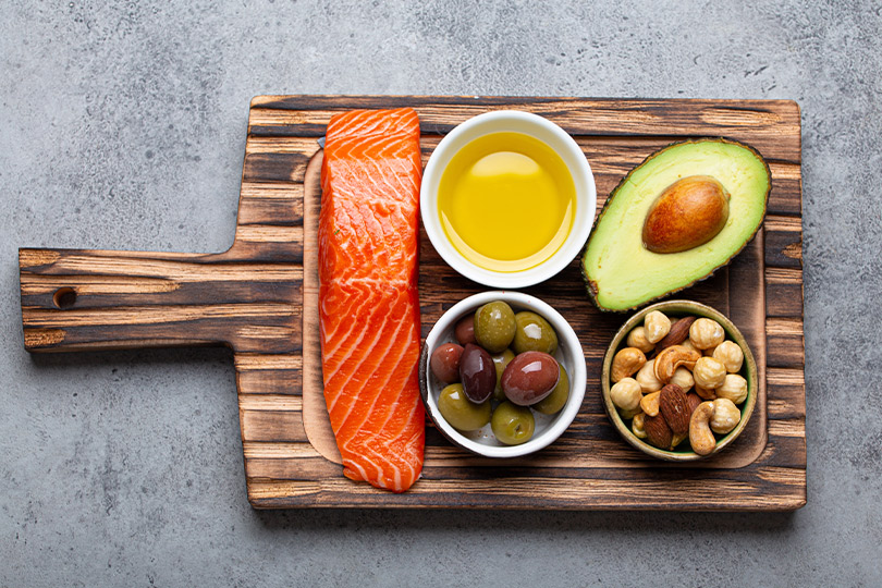 A wooden cutting board filled with various foods, including vegetables and fruits, related to natural winter pain relief.
