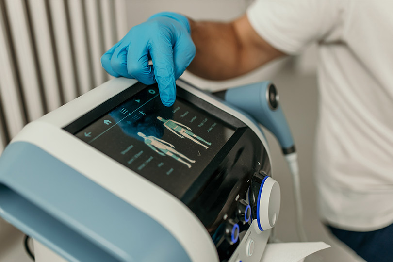 An individual wearing blue gloves operates a scanning machine on a patient, showcasing advancements in pain management.