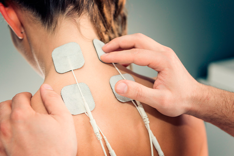 A woman demonstrates a neck pain relief device on her back, showcasing options for relief in Mission.