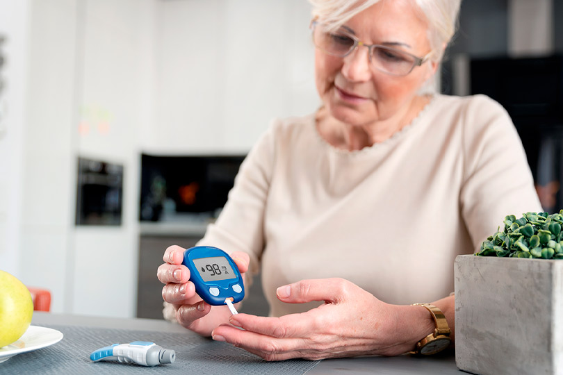 Senior woman with glucometer checking blood sugar level at home. Diabetes, health care concept